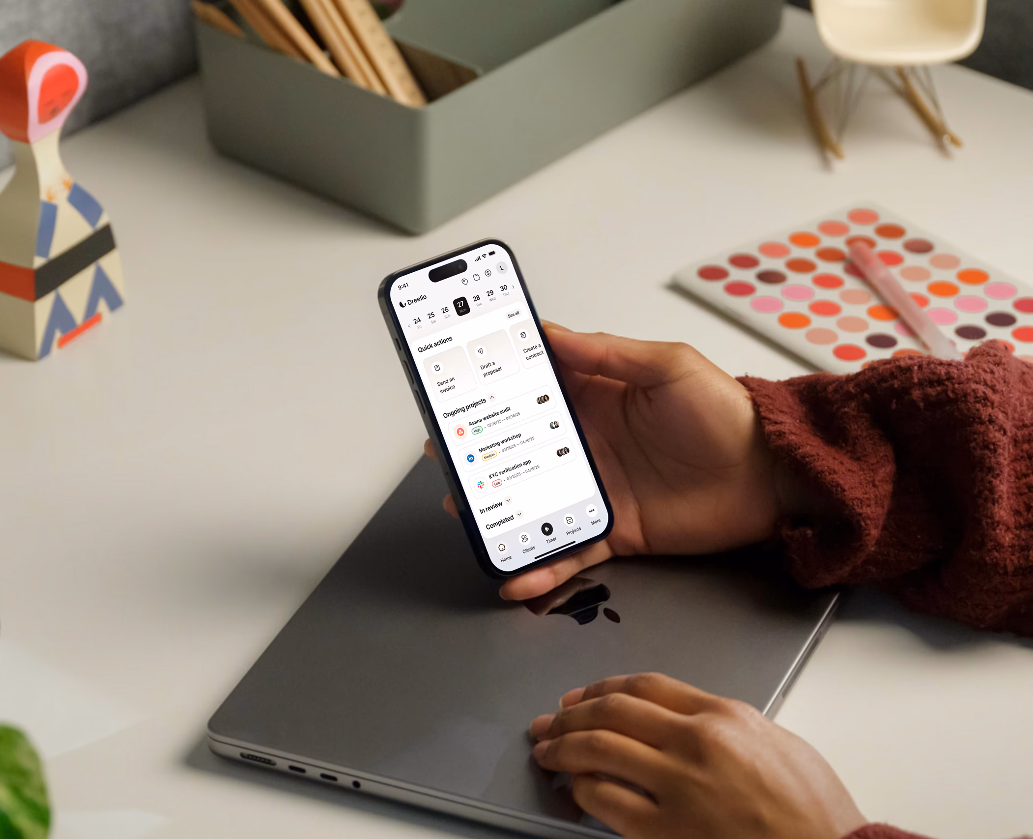 App Boflow no celular — mão segurando smartphone sobre laptop